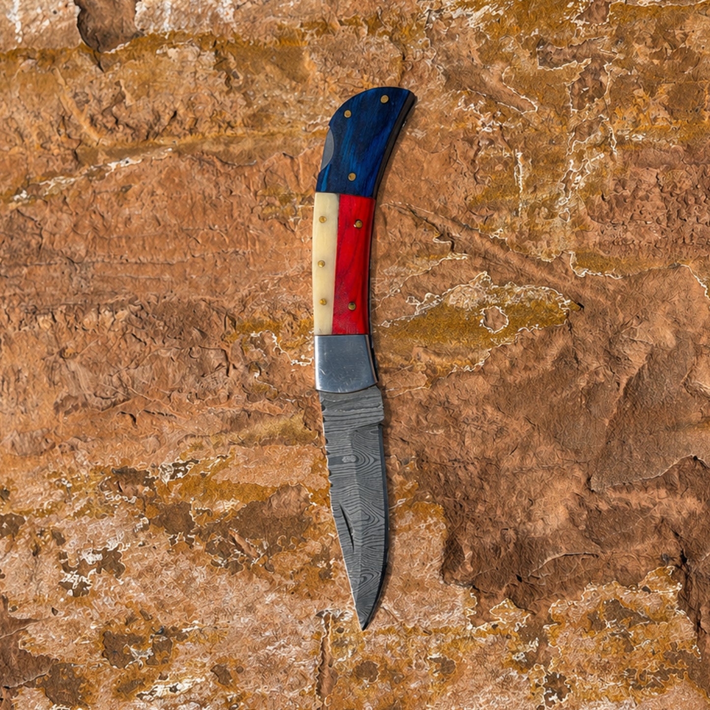 Liberty Fang Folder Damascus folding knife with leather belt sheath on rock background