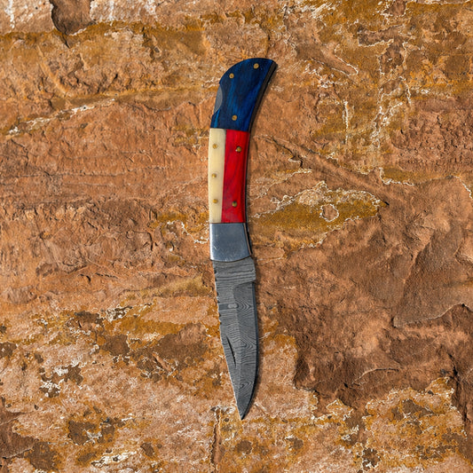 Liberty Fang Folder Damascus folding knife with leather belt sheath on rock background