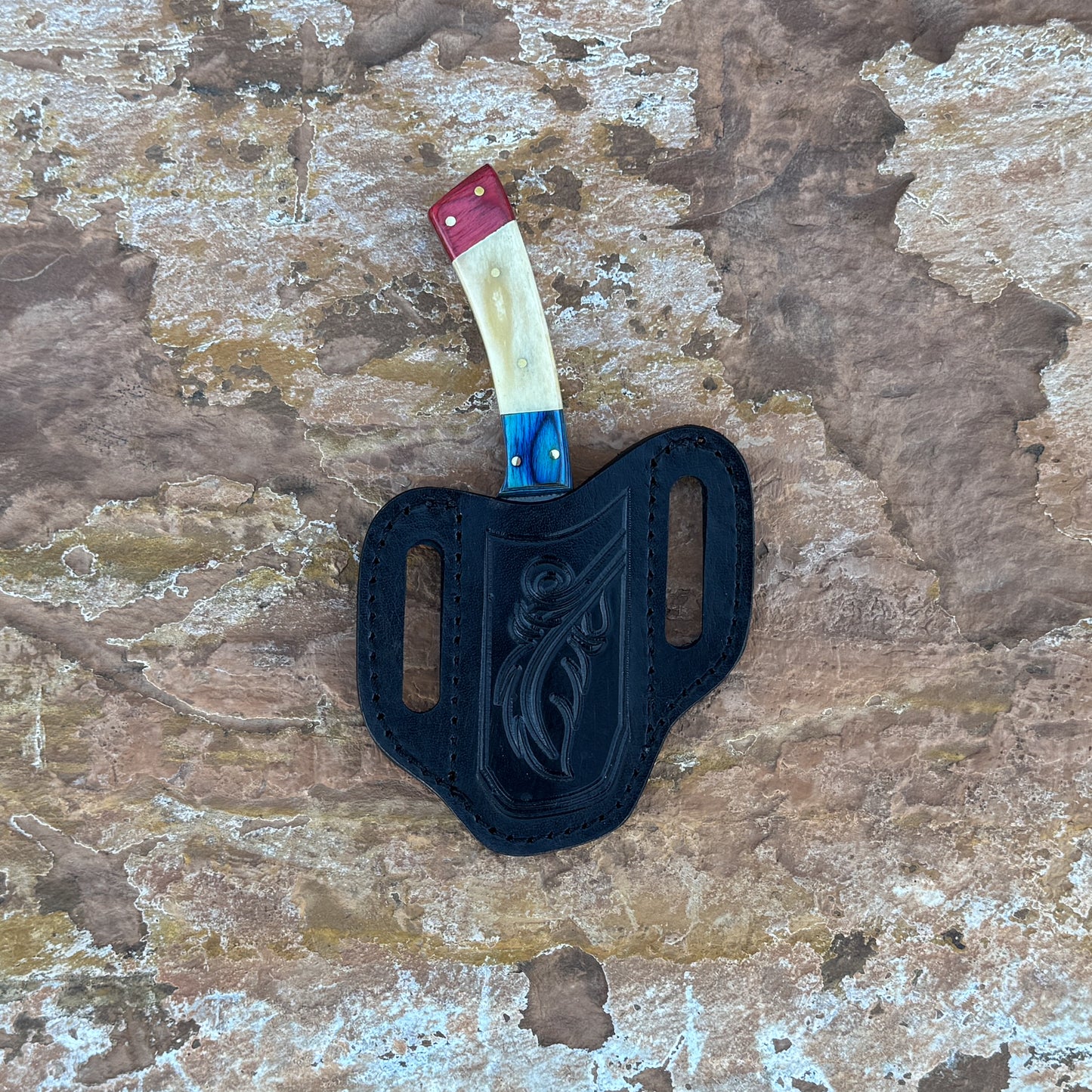A full-tang D2 steel hunting knife featuring a red dyed wood, natural camel bone, and blue dyed-wood tri-color handle, displayed on desert rock. Designed for skinning, slicing, and rugged outdoor field use.