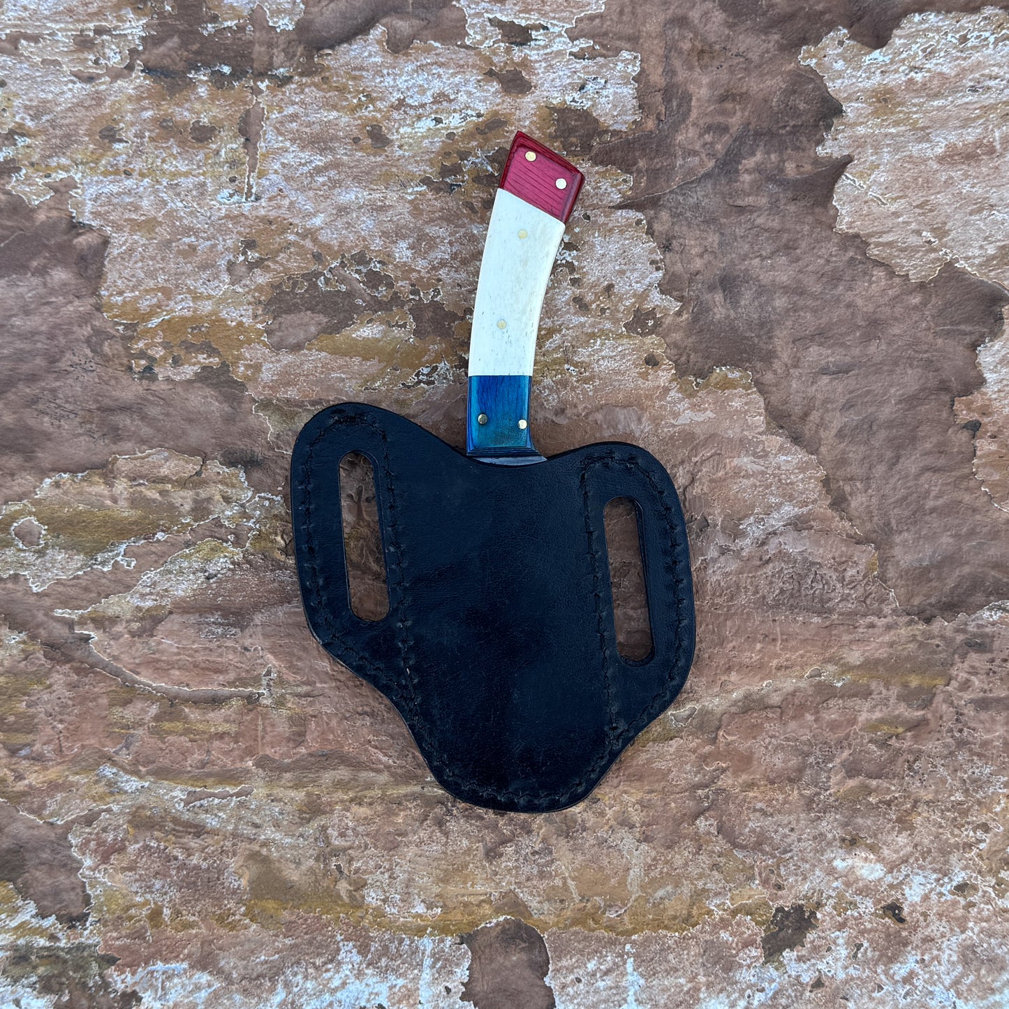 A full-tang D2 steel hunting knife featuring a red dyed wood, natural camel bone, and blue dyed-wood tri-color handle, displayed on desert rock. Designed for skinning, slicing, and rugged outdoor field use.