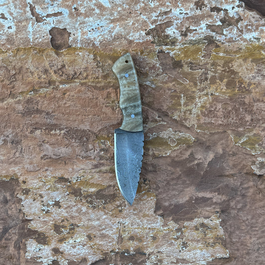 Sandstorm Skinner Damascus knife with sand-toned resin handle

Patterned Damascus blade with swirling wave design

Pearlescent desert resin handle close-up

Skinner knife displayed on brown leather sheath

Sandstorm Skinner arranged on natural wood background

Precision skinner in natural lighting

Blue Spade Forge Sandstorm Skinner held in hand for scale

Damascus skinner blade and resin handle product showcase