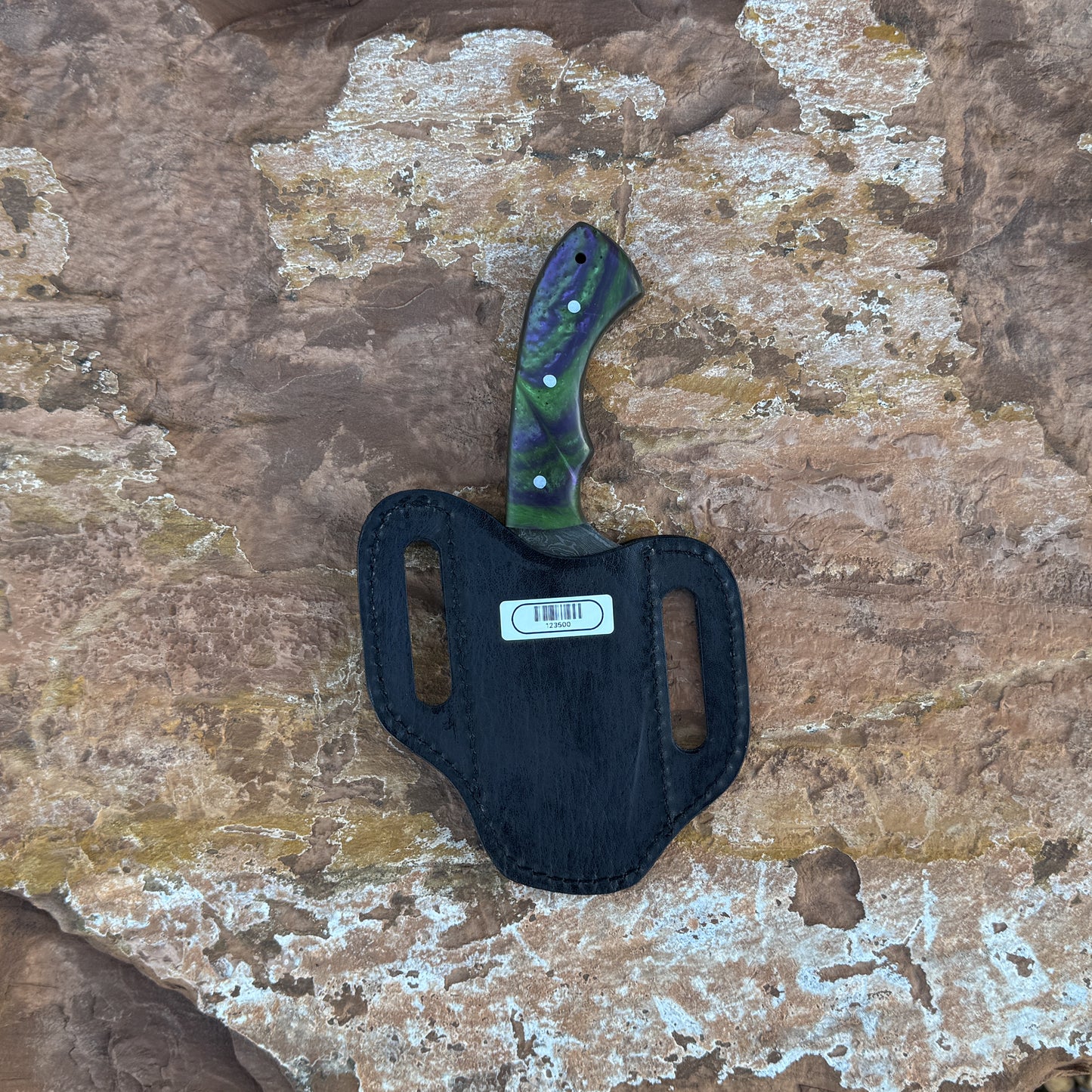 Vortex Fang Damascus fixed blade knife with swirling resin handle

Close-up of patterned Damascus blade with wave design

Resin-cast handle with multicolor swirl detail

Vortex Fang knife displayed on brown leather sheath

Knife and sheath arranged on natural wood background

Outdoor knife with resin handle in natural lighting

Blue Spade Forge Vortex Fang held in hand for size reference

Damascus blade and resin handle close-up product showcase
