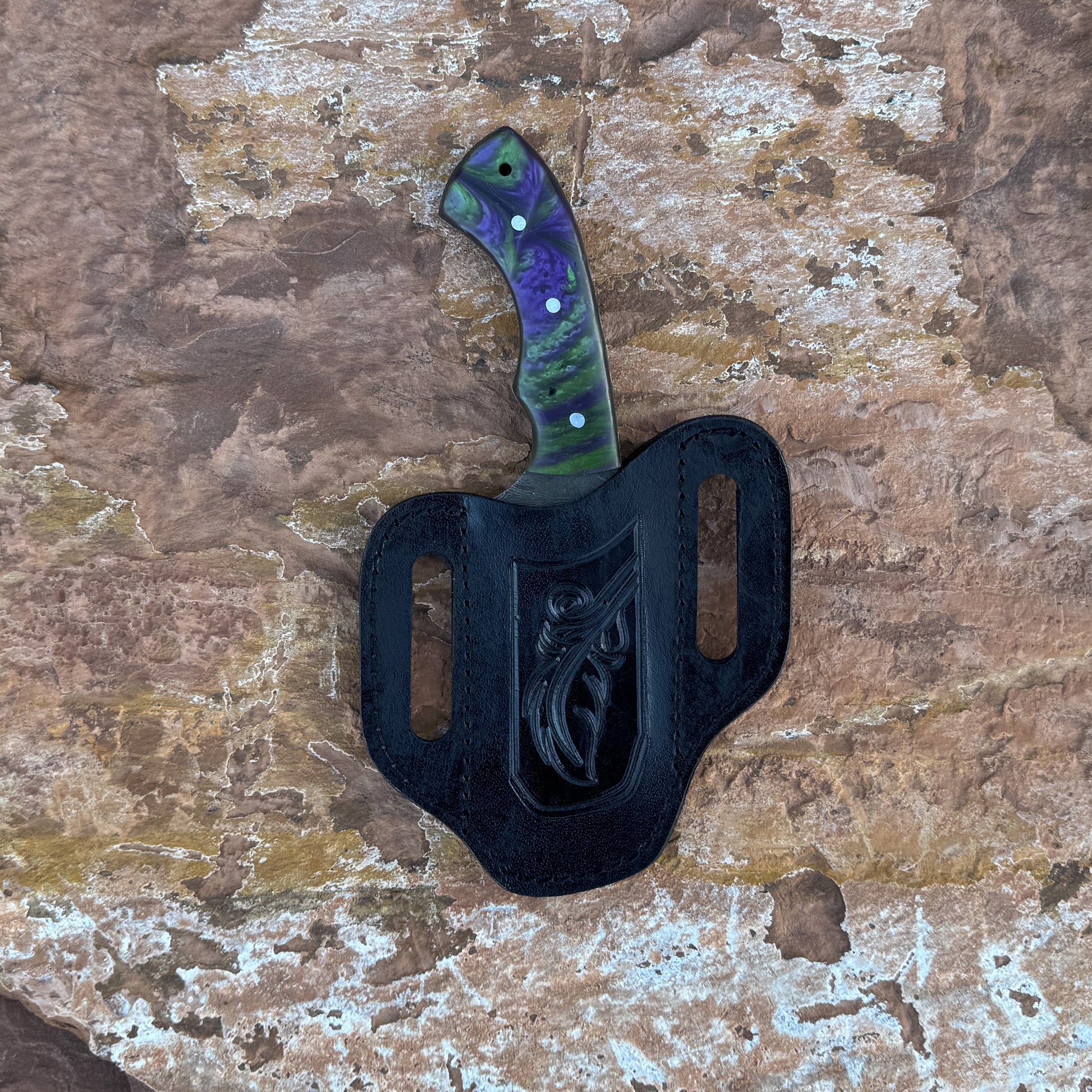 Vortex Fang Damascus fixed blade knife with swirling resin handle

Close-up of patterned Damascus blade with wave design

Resin-cast handle with multicolor swirl detail

Vortex Fang knife displayed on brown leather sheath

Knife and sheath arranged on natural wood background

Outdoor knife with resin handle in natural lighting

Blue Spade Forge Vortex Fang held in hand for size reference

Damascus blade and resin handle close-up product showcase