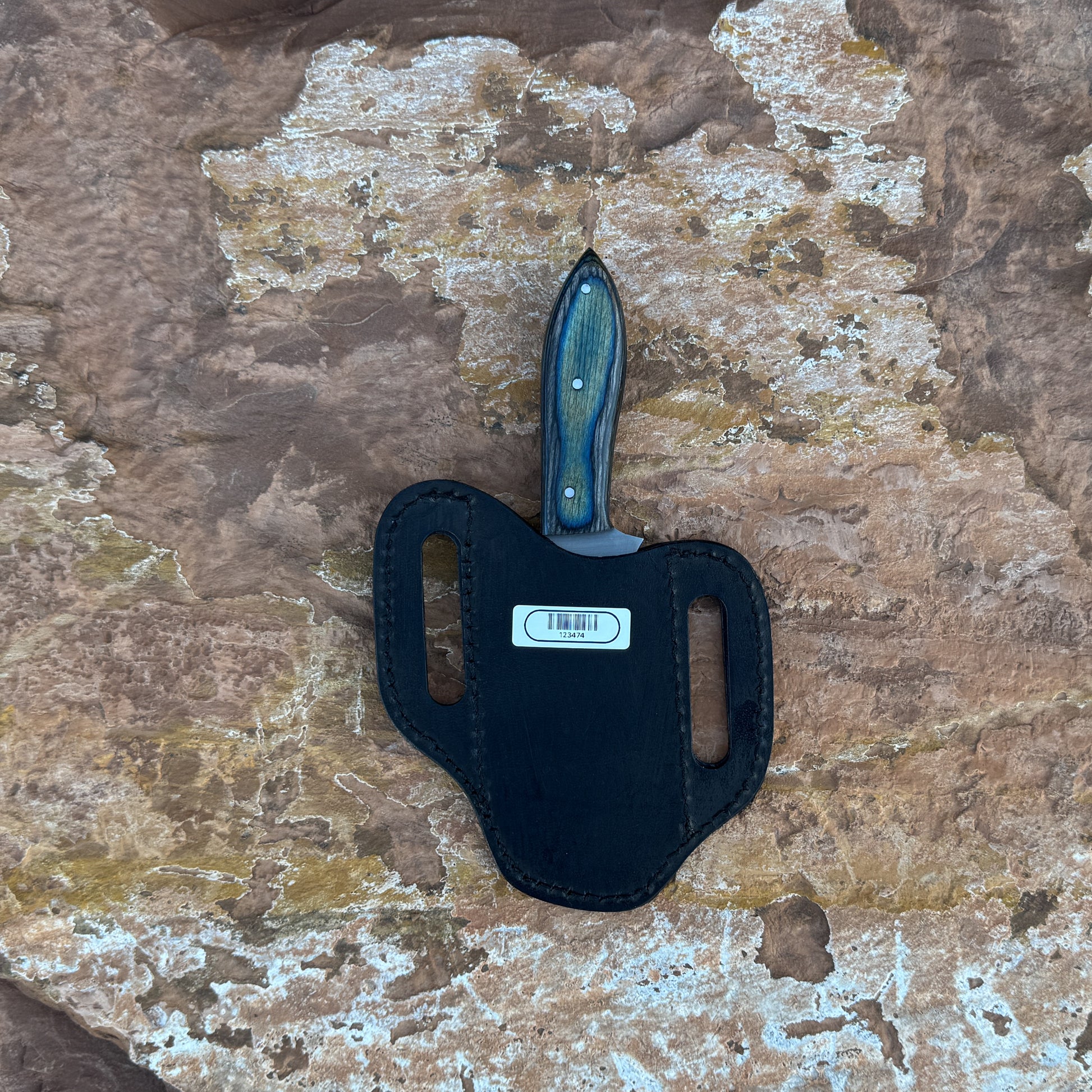 A full-tang clip-point hunting knife with a razor-sharp high-carbon steel blade and a blue-tinted wooden handle featuring bold grain patterns, shown with its hand-stitched leather sheath. Designed by Blue Spade Forge for hunting, field dressing, skinning, and rugged outdoor use.