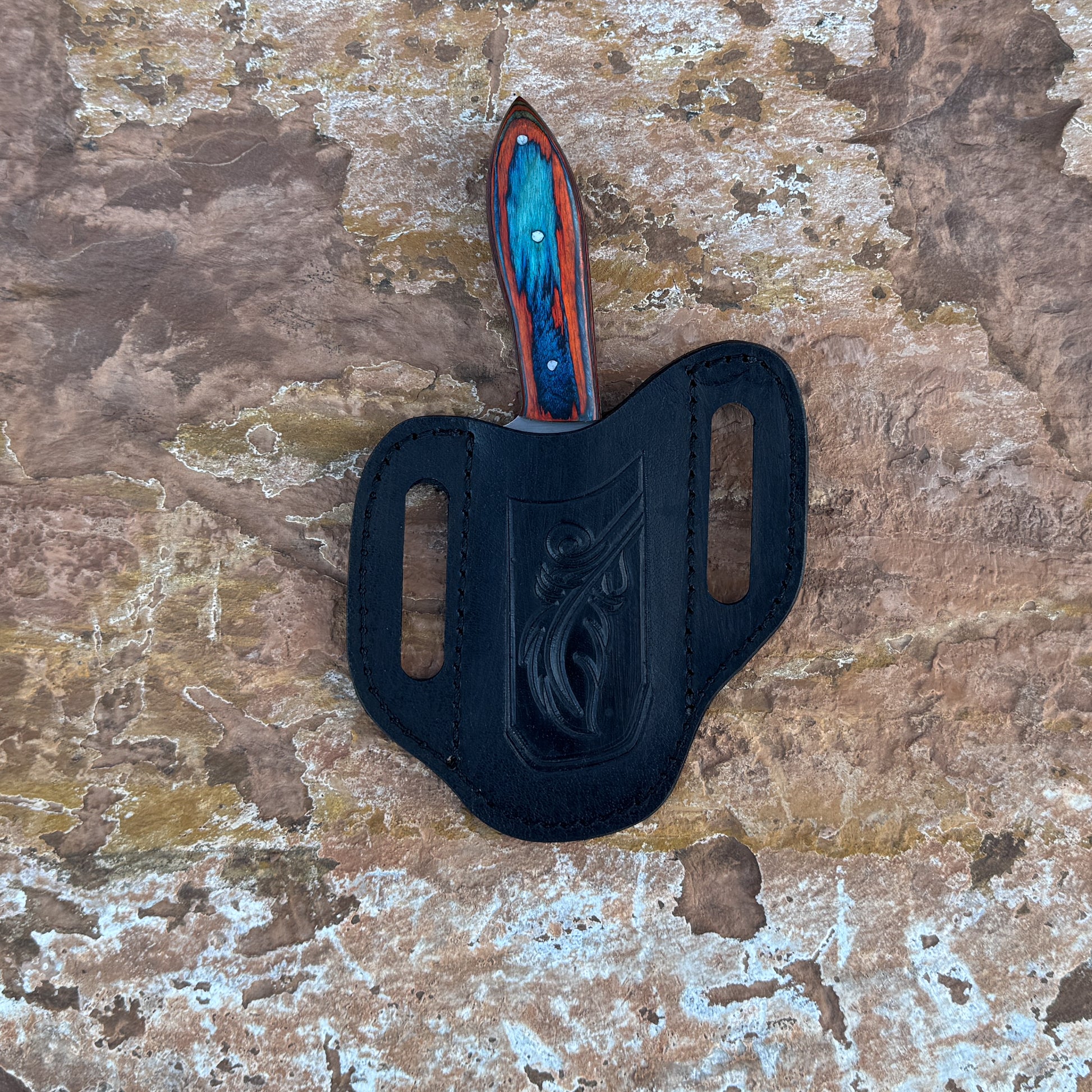 Blaze Creek Bowie knife with multicolored wood handle

Full-tang bowie knife on hand-stitched leather sheath

Clip-point blade close-up for slicing and skinning

Vivid blue, green, and red wood handle detail

Outdoor bowie knife displayed on natural wood

Triple-rivet handle construction on Blaze Creek

Blue Spade Forge Blaze Creek in natural lighting

Bowie knife and sheath arranged for product showcase