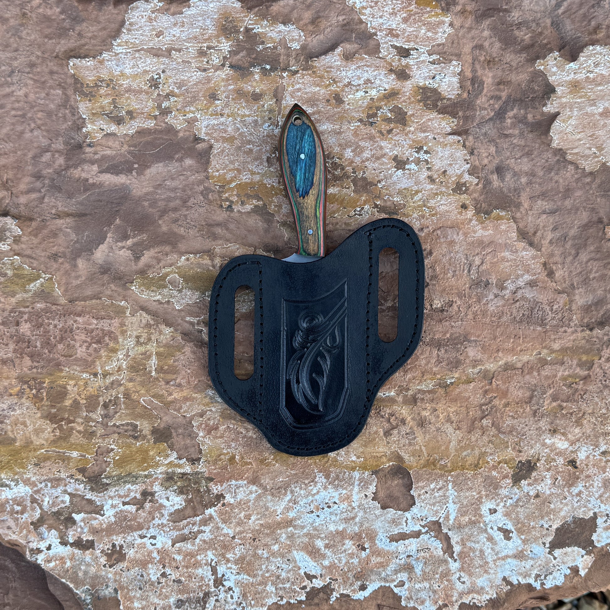 Ridge Cowboy knife with squared cowboy-style blade

Compact cowboy knife displayed on hand-stitched leather sheath

Close-up of multi-tone hardwood handle grain

Ridge Cowboy knife on natural wood background

Knife and leather sheath arranged for product display

Outdoor cowboy-style knife in natural lighting

Blue Spade Forge Ridge Cowboy held in hand for scale

Detail shot of squared blade and multi-tone handle