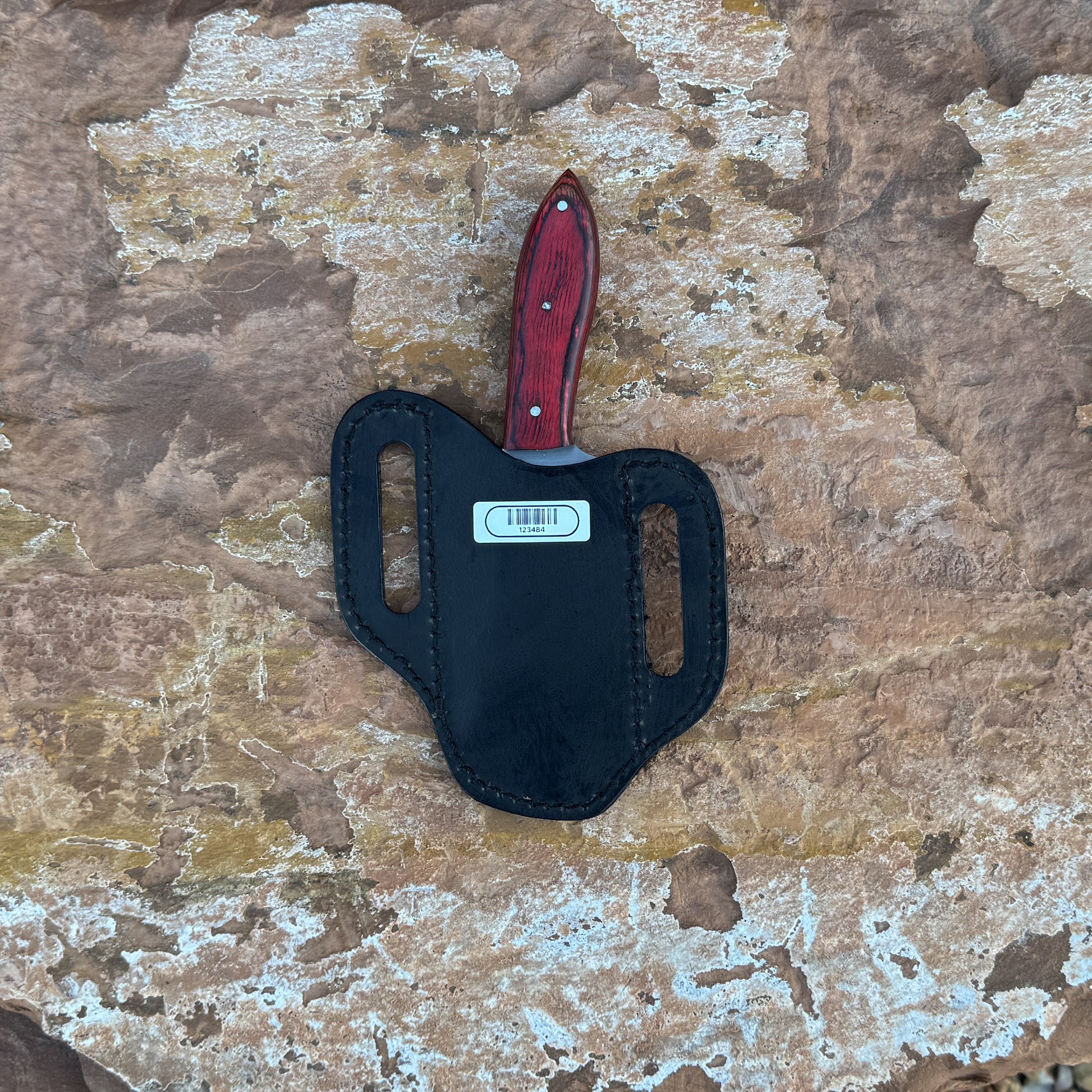 A full-tang fixed blade knife with a high-carbon steel blade and a deep red hardwood handle featuring bold grain patterns, shown with its hand-stitched brown leather sheath. Crafted by Blue Spade Forge for rugged outdoor tasks, carving, slicing, and field use.