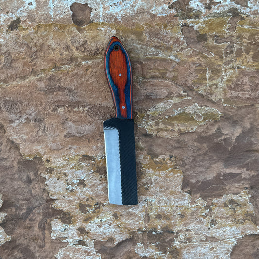 Red Ember Rasp Cleaver with red and blue hardwood handle

Close-up of rasp-textured spine on cleaver blade

Cleaver-style knife displayed on hand-stitched leather sheath

Full-tang cowboy cleaver on rustic wood background

Handle detail showing red-blue grain and brass hardware

Blade profile highlighting chopping edge and spine texture

Blue Spade Forge Red Ember Cleaver held in hand for scale

Leather sheath detail with stitching and natural finish