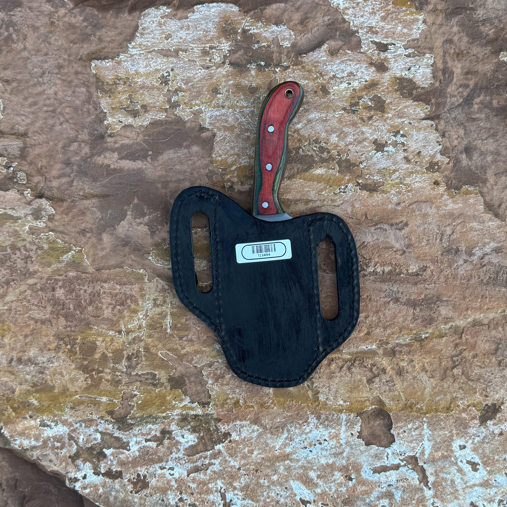 A full-tang stainless-steel field knife with a dyed-wood handle featuring rich grain patterns and vibrant coloration, shown with its handmade leather sheath. Designed by Blue Spade Forge for outdoor use, camping, and field tasks.