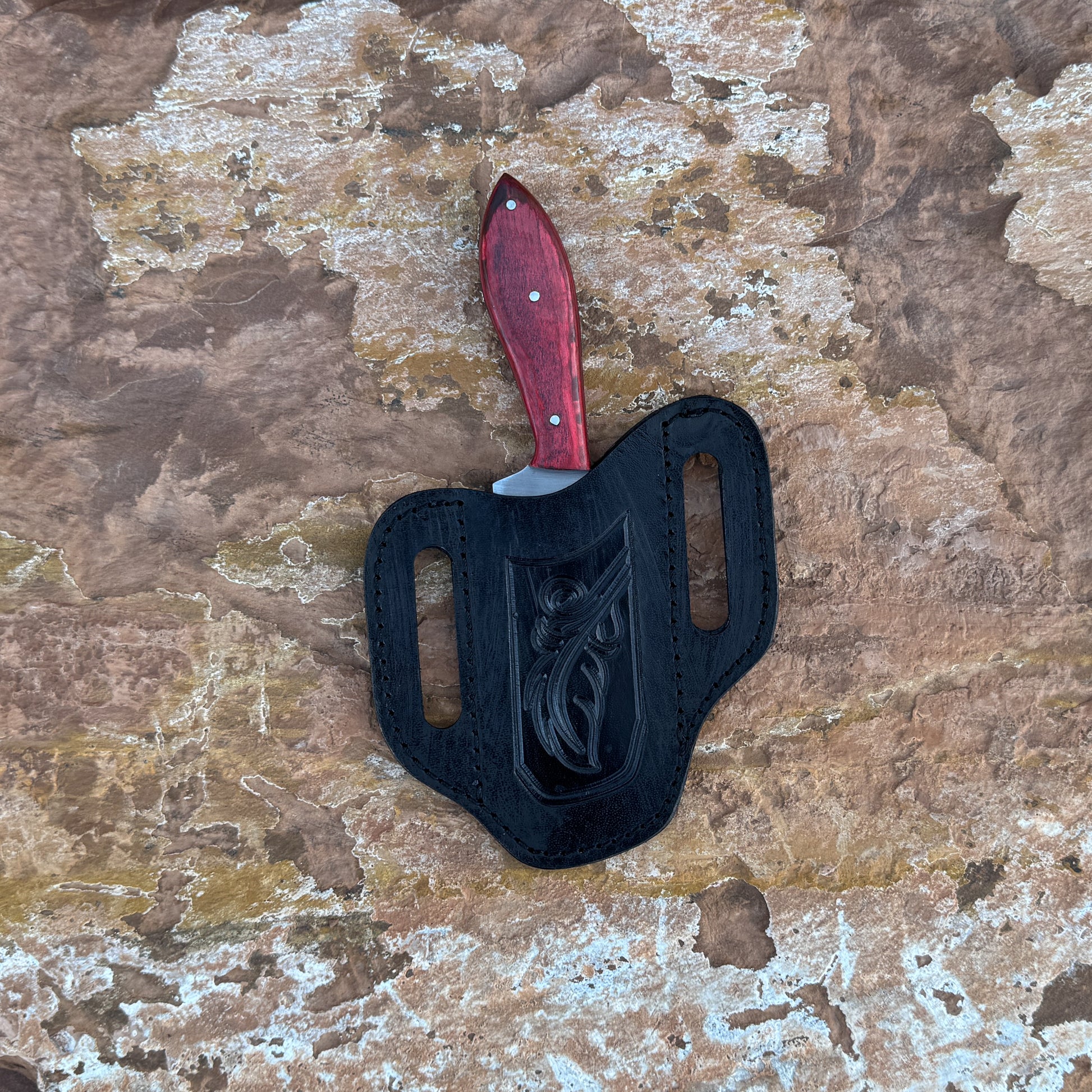 Scarlet Chop cowboy-style knife with squared 1095 blade

Close-up of red dyed hardwood handle

Compact cowboy knife shown with leather sheath

Blade detail showing squared chopping profile

Knife on rustic wood background

Scarlet Chop displayed with hand-stitched brown sheath

Blue Spade Forge Scarlet Chop held in hand for scale

Detail shot of blade edge and red handle grain