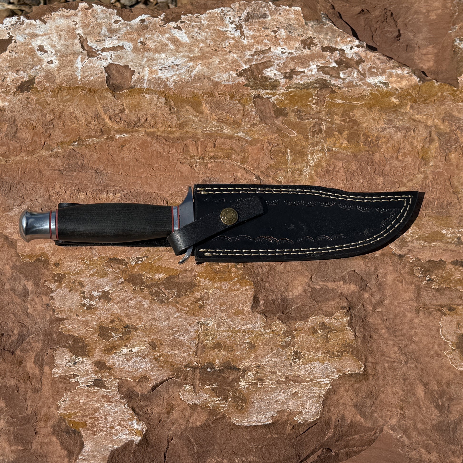 Iron Talon Bowie knife with leather sheath showing full tang Damascus blade and rugged outdoor setup
